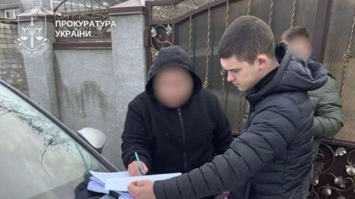 У Києві шахраї викрали 20 млн грн підробивши паспорт директора Слідчий прокуратури вручає повідомлення про підозру чоловіку з розмитим обличчям біля автомобіля у справі про шахрайство з підробкою паспорта