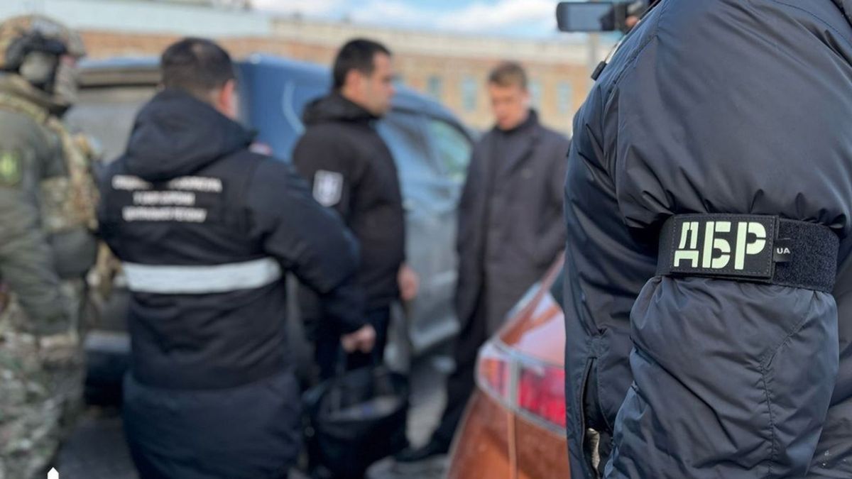 У Києві та на Волині судитимуть двох військових посадовців за корупцію в ТЦК кілька чоловіків у формі та бронежилетах стоять біля автомобілів, на передньому плані видно співробітника з нашивкою «ДБР»