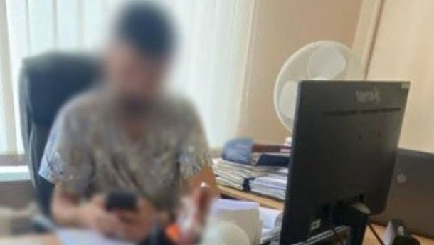 У Києві директорку автошколи підозрюють у продажу фіктивних свідоцтв про навчання Чоловік у кабінеті сидить за столом із документами та комп’ютером, тримаючи телефон у руках