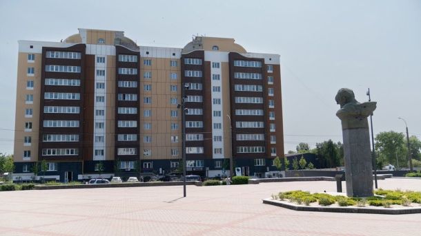 З Кирилівського озера відкачали 25 кубів нафти після обстрілу Сучасна багатоповерхівка з коричневими й бежевими фасадами, перед якою на площі встановлений пам’ятник у вигляді бюста на високому постаменті