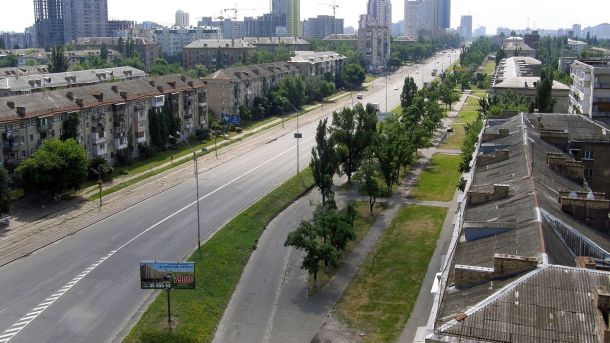 «Будинок з хлібною лавкою»: замість реставрації — сучасні двері з монтажною піною Вулиця в Києві з деревами і будинками, сучасний міський пейзаж, спокійна атмосферу, забудова та зелені зони у центрі міста.