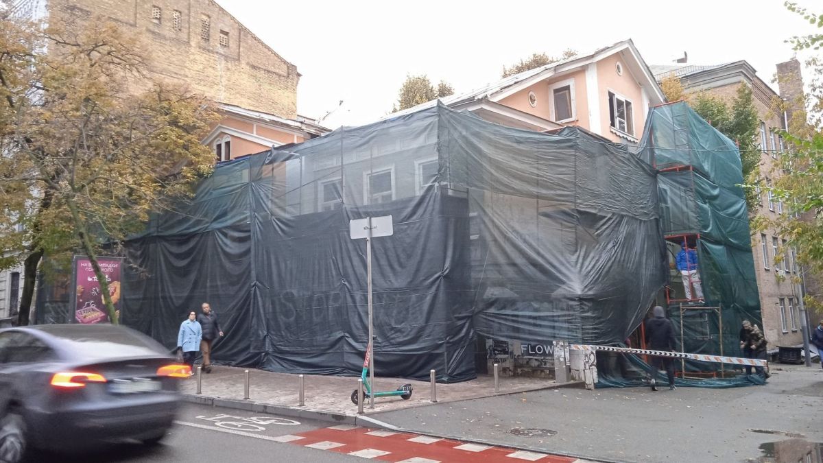 На Ярославовому Валу триває руйнування пам’ятки — судові заборони та приписи не діють (фото) Будівля, вкрита темною сіткою для реставрації, уздовж вулиці з осінніми деревами