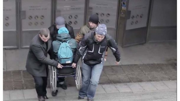 Київавтодор оголосив тендер на ремонт вулиці Героїв Маріуполя — вперше з 1984 року Люди допомагають людині на інвалідному візку подолати сходи біля входу до будівлі — проблема безбар'єрного простору в Україні