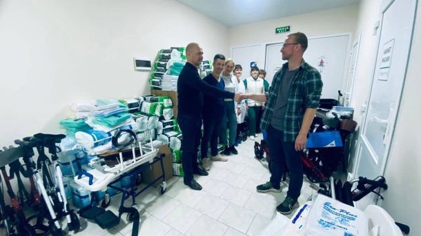 Фастівчанка Наталія Докієнко виборола три медалі на чемпіонаті світу з драгонботу в Німеччині У кімнаті стоять люди, один чоловік потискає руку іншому, поруч складені ходунки та медичні засоби
