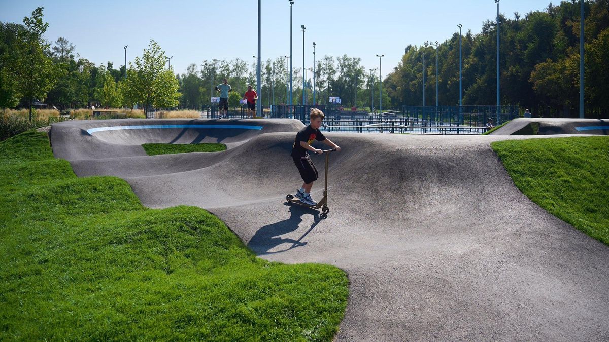 На ВДНГ відкрили новий асфальтний pump track і оновили Урбан-парк Хлопчик катається на самокаті у скейт-парку з хвилястими бетонними доріжками