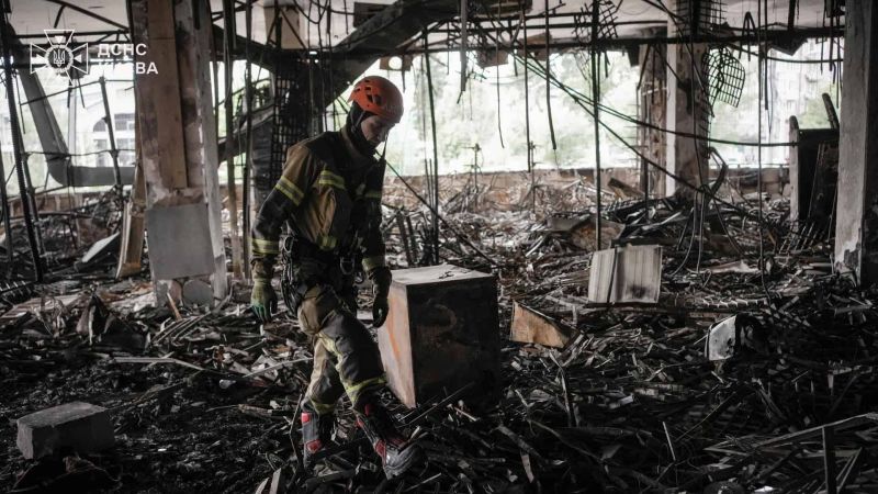 Головні новини Києва | Kyiv.News Рятувальник ДСНС Києва в помаранчевій касці розбирає завали у повністю знищеній пожежею будівлі після ворожого обстрілу