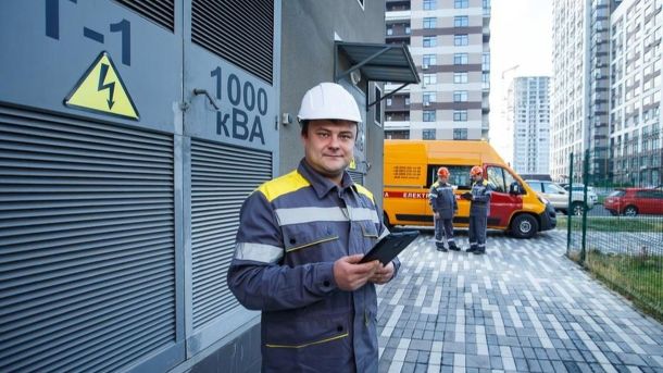 ДТП за участю маршрутки та легковика на проспекті Науки у Києві Електрик у захисному одязі стоїть біля трансформаторної підстанції, тримаючи планшет