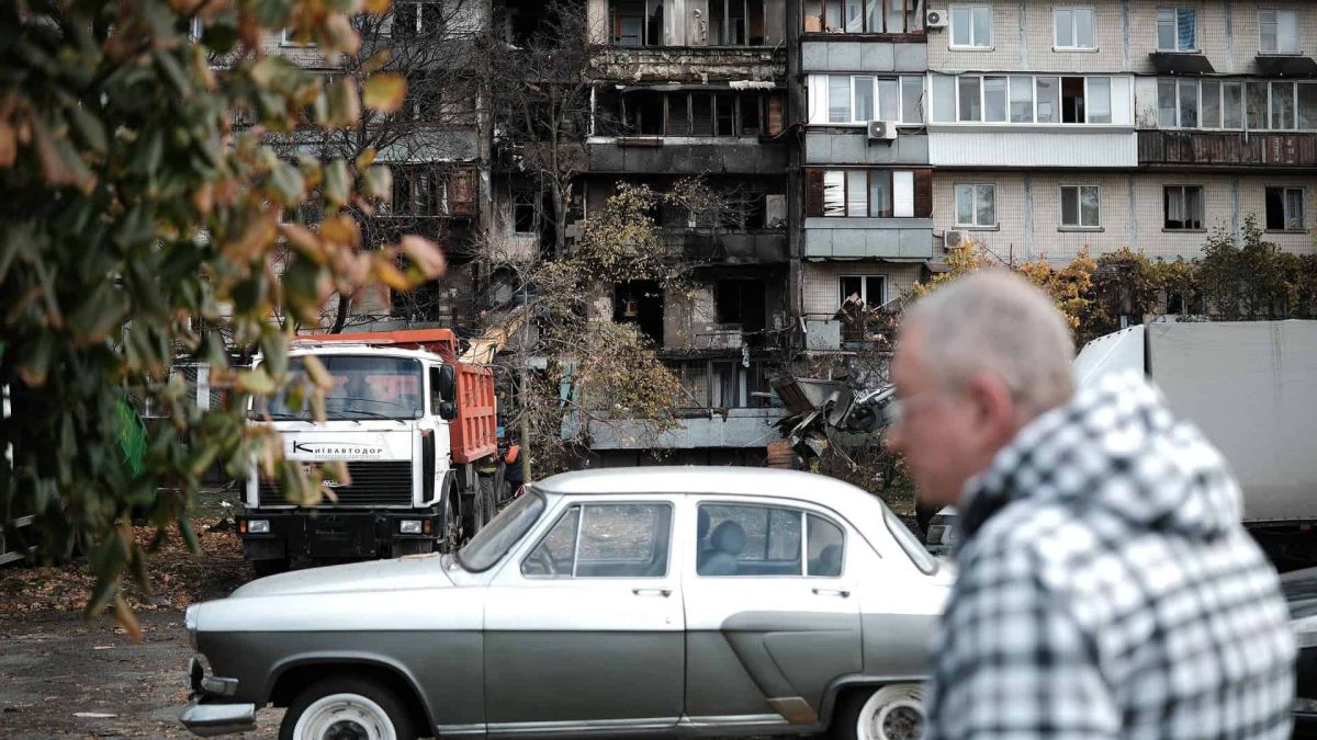 22 000 киян отримали компенсацію за пошкоджене житло Чоловік проходить повз зруйнованої багатоповерхівки у Києві, біля будинку стоїть вантажівка, яка вивозить будівельні завали після прильоту