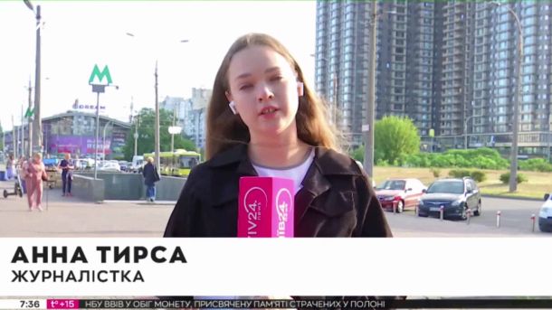 Автобуси №46 і №112 змінять маршрут 21 квітня через ярмарок Журналістка веде репортаж біля станції метро Мінська в Києві, позаду припарковані автомобілі на тротуарі