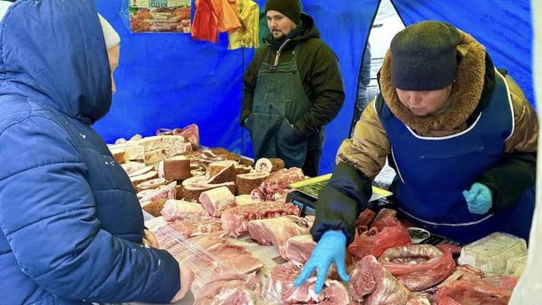 Вихідні у Києві 6-7 червня: Jumpalooza, Ціммер і виставка Гавриленка Продавець у рукавичках обслуговує покупця на зимовому м'ясному ярмарку під синім наметом