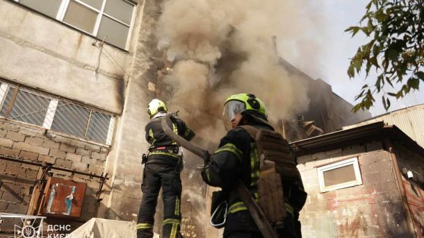 Атака на Київ 4 квітня: пожежа у Дарницькому р-ні на даху будівлі Двоє рятувальників ДСНС Києва направляють пожежний рукав на задимлену будівлю після атаки 2 червня