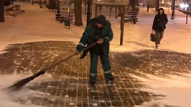 Київ засніжило: 264 одиниці техніки на вулицях, очищають магістралі, мости та пішохідні зони Чоловік очищає сніг