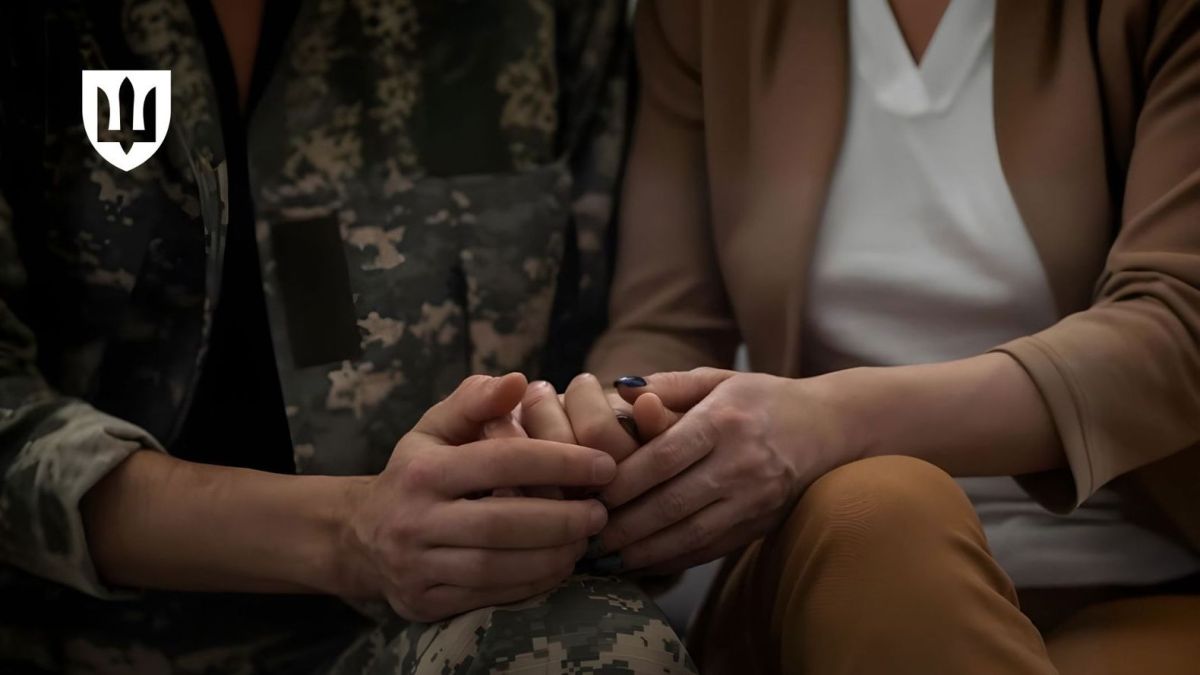 У Києві відкрили групи психологічної підтримки для дружин полонених і зниклих Захисників Рука військовослужбовця у піксельній камуфляжній формі ніжно тримає руку жінки в діловому одязі