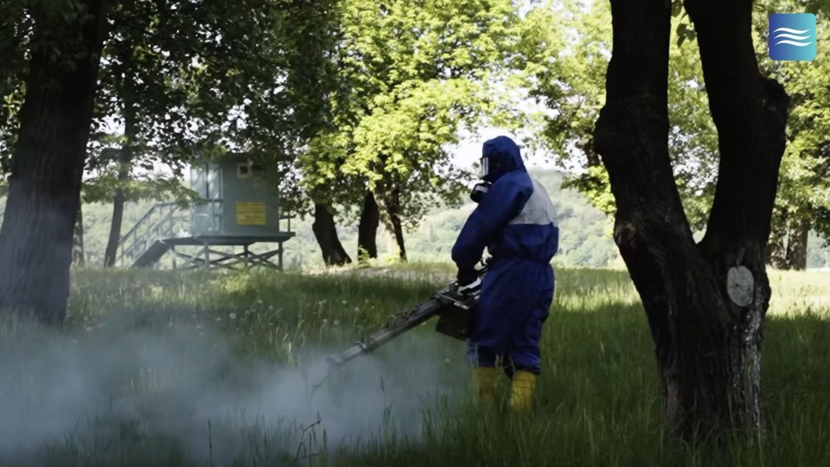 Труханів острів та озера Києва: сьогодні обробка від кліщів Працівник у захисному костюмі та жовтих гумових чоботах проводить дезінсекцію парку