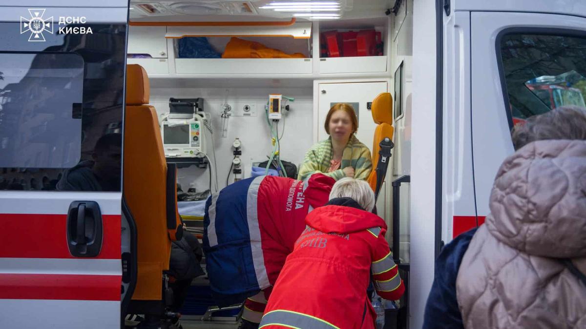 Кількість постраждалих у Києві після атаки РФ зросла до 29 осіб Дівчина сидить в кареті швидкої допомоги і лікарі надають їй допомогу