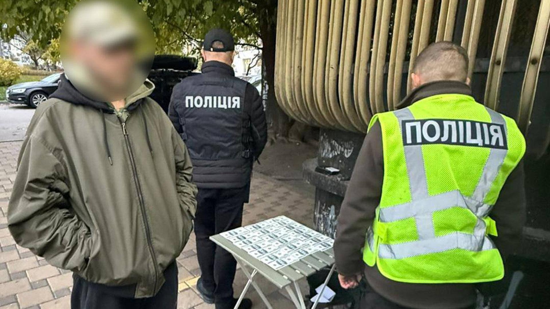 Кілька правоохоронців стоять біля столика, на якому розкладені доларові купюри