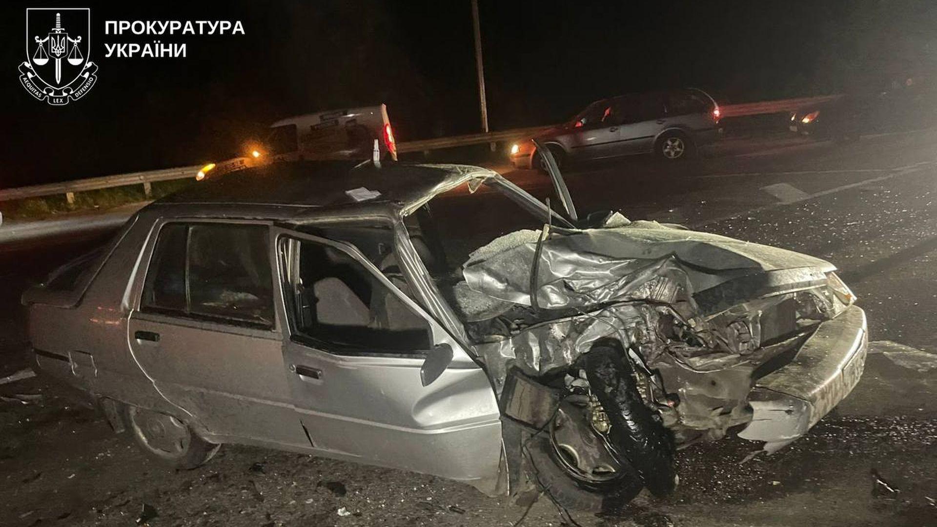 Сильно пошкоджений сріблястий легковий автомобіль після лобового зіткнення вночі на дорозі