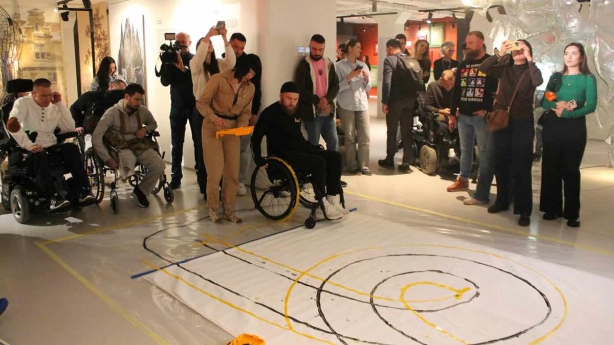 Ветеран малює кріслом колісним і збирає кошти на ЗСУ Ветеран війни на кріслі колісному малює картину він колесами робить кола по паперу на підлозі, залишаючи сліди фарби