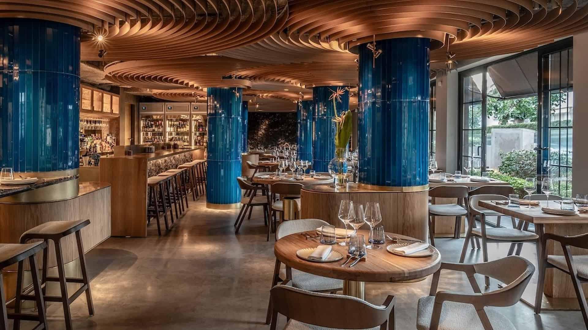 Панорамний вид ресторану з круглими столами та синіми колонами