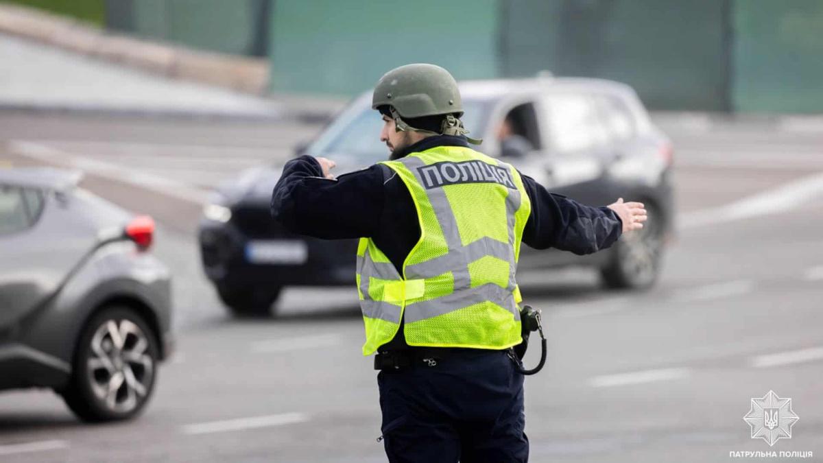 Патрульний поліцейський стоїть на дорозі і регулює рух автомобілів