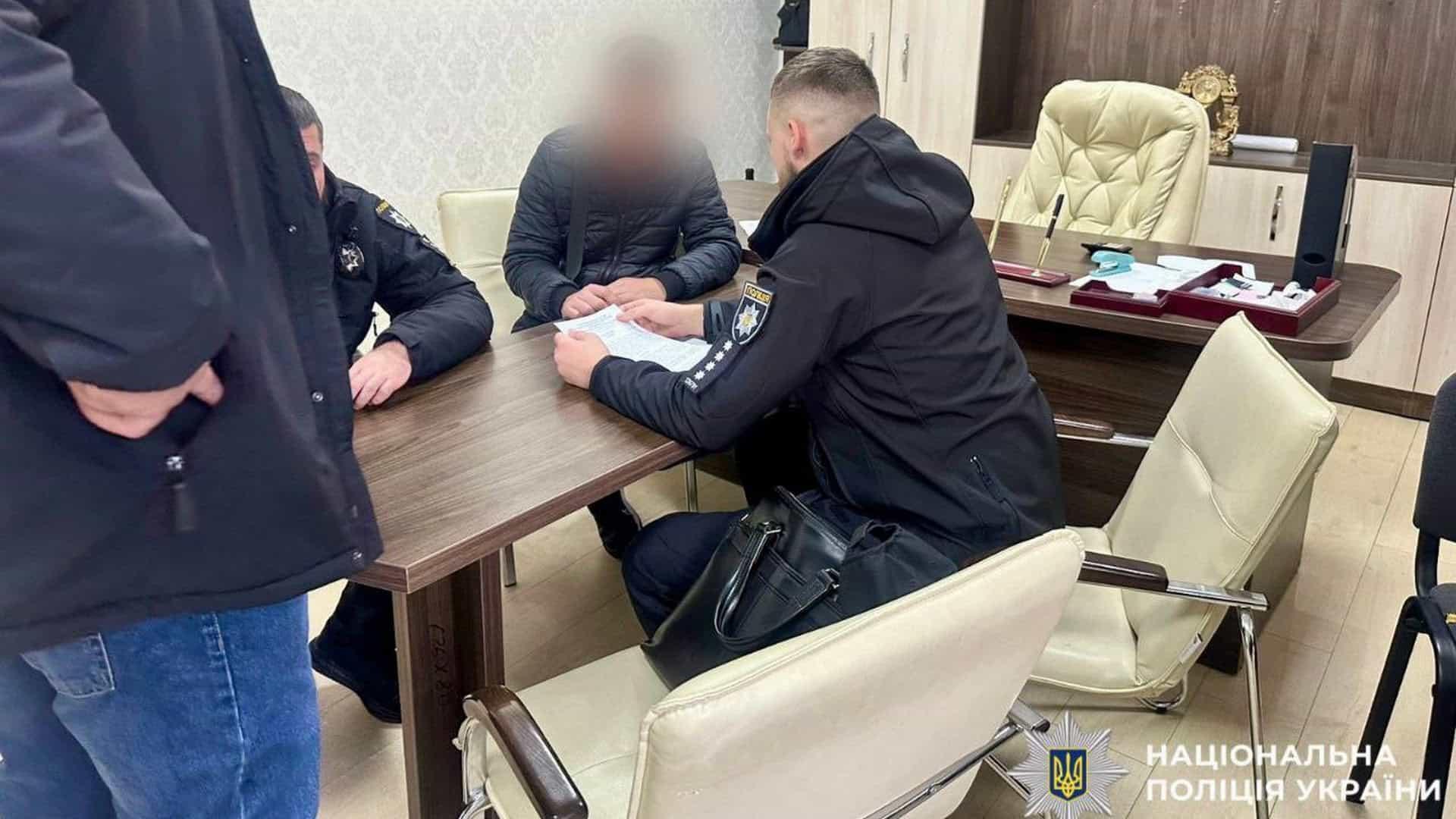 Правоохоронці сидять за столом в офісі поряд із підозрюваним у скоєнні злочину