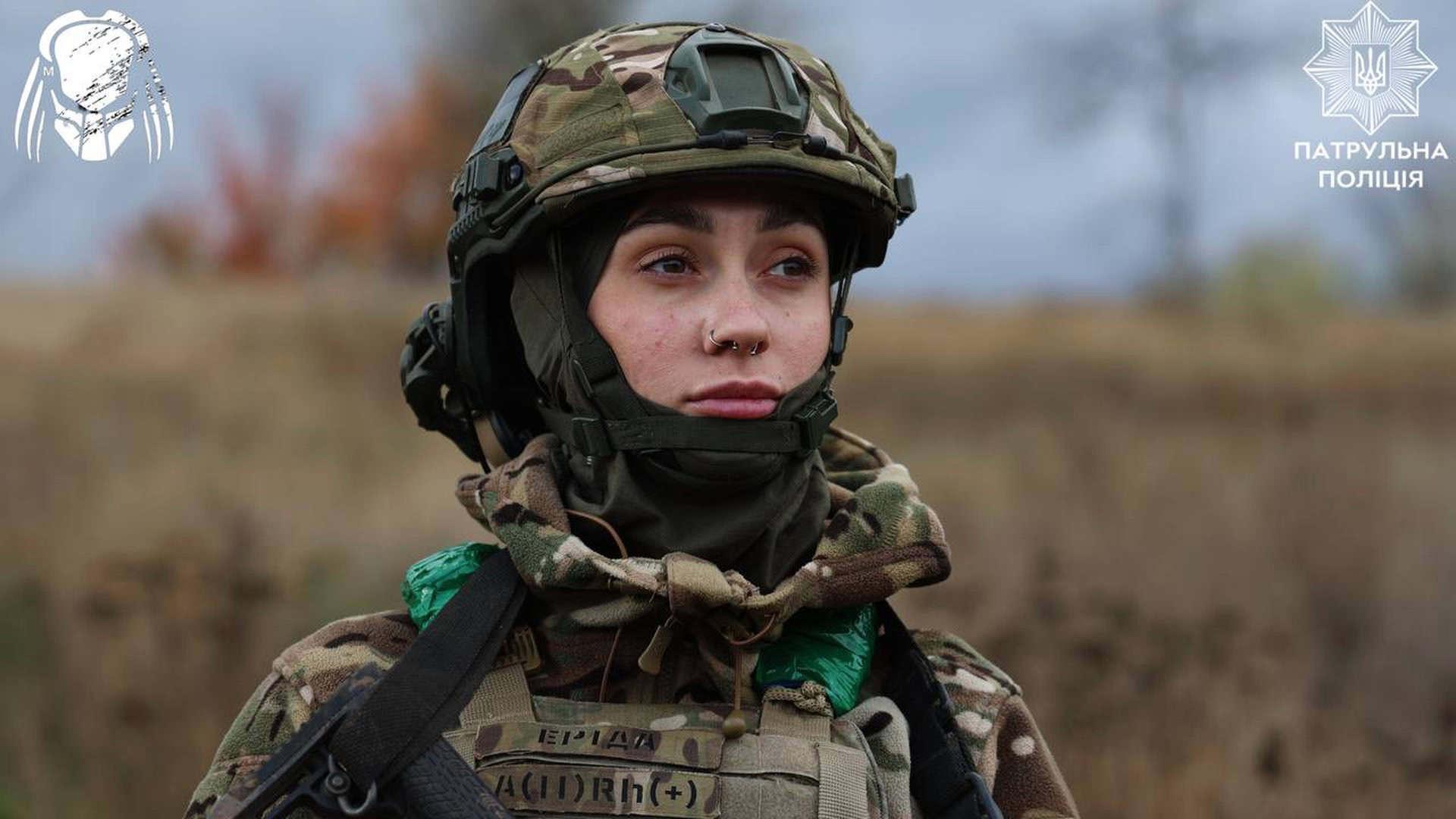 Жінка-військовослужбовець у камуфляжі та шоломі уважно дивиться вдалину