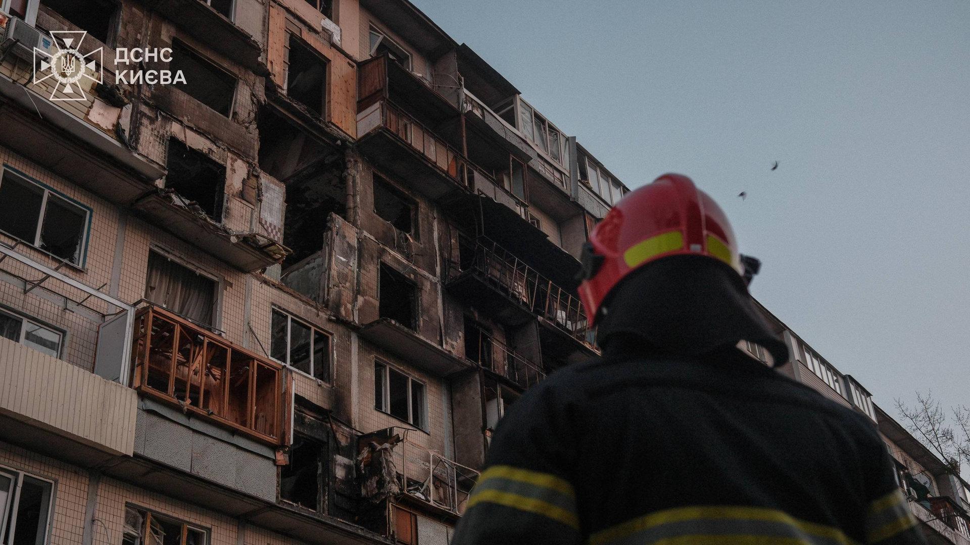 Рятувальник дивиться на згорілі квартири в багатоповерхівці