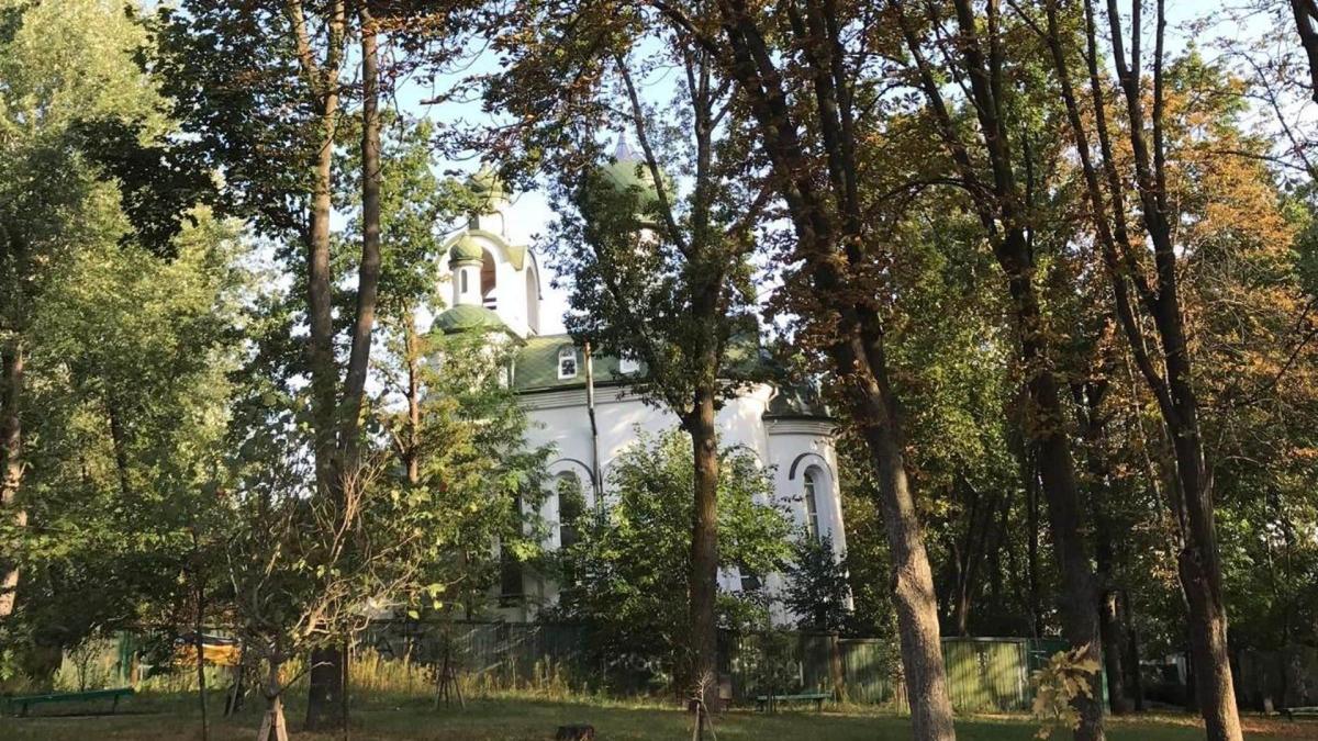 Суд зобов’язав Київраду надати «Крістеровій гірці» статус заповідного об’єкта Церква з білими стінами та зеленими куполами, яка визирає крізь дерева в парку