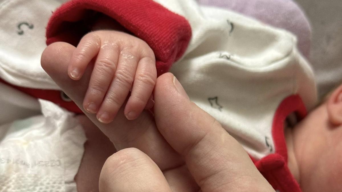 Ручку новонародженої дитини тримає доросла рука