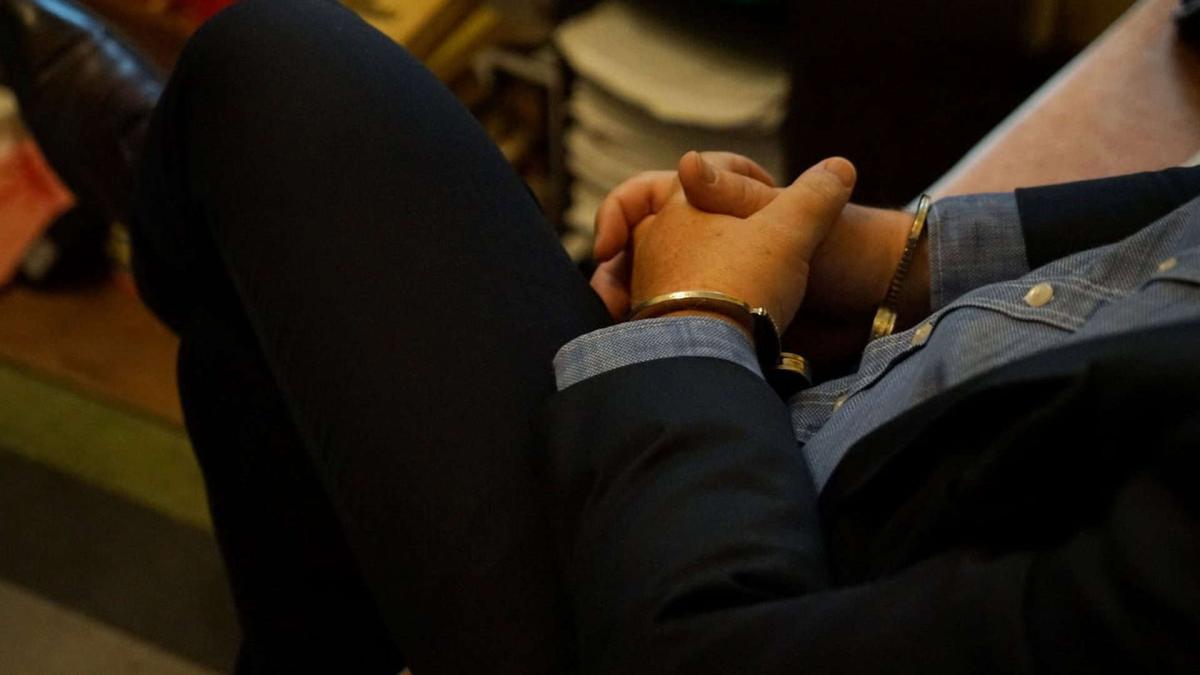 Громадянина Польщі викрили на сексуальній експлуатації 8 дітей з України Фігура чоловіка тільки без голови, видно руки в наручниках, він сидить в темному костюмі, синій сорочці і в класичних шкіряних чоботях