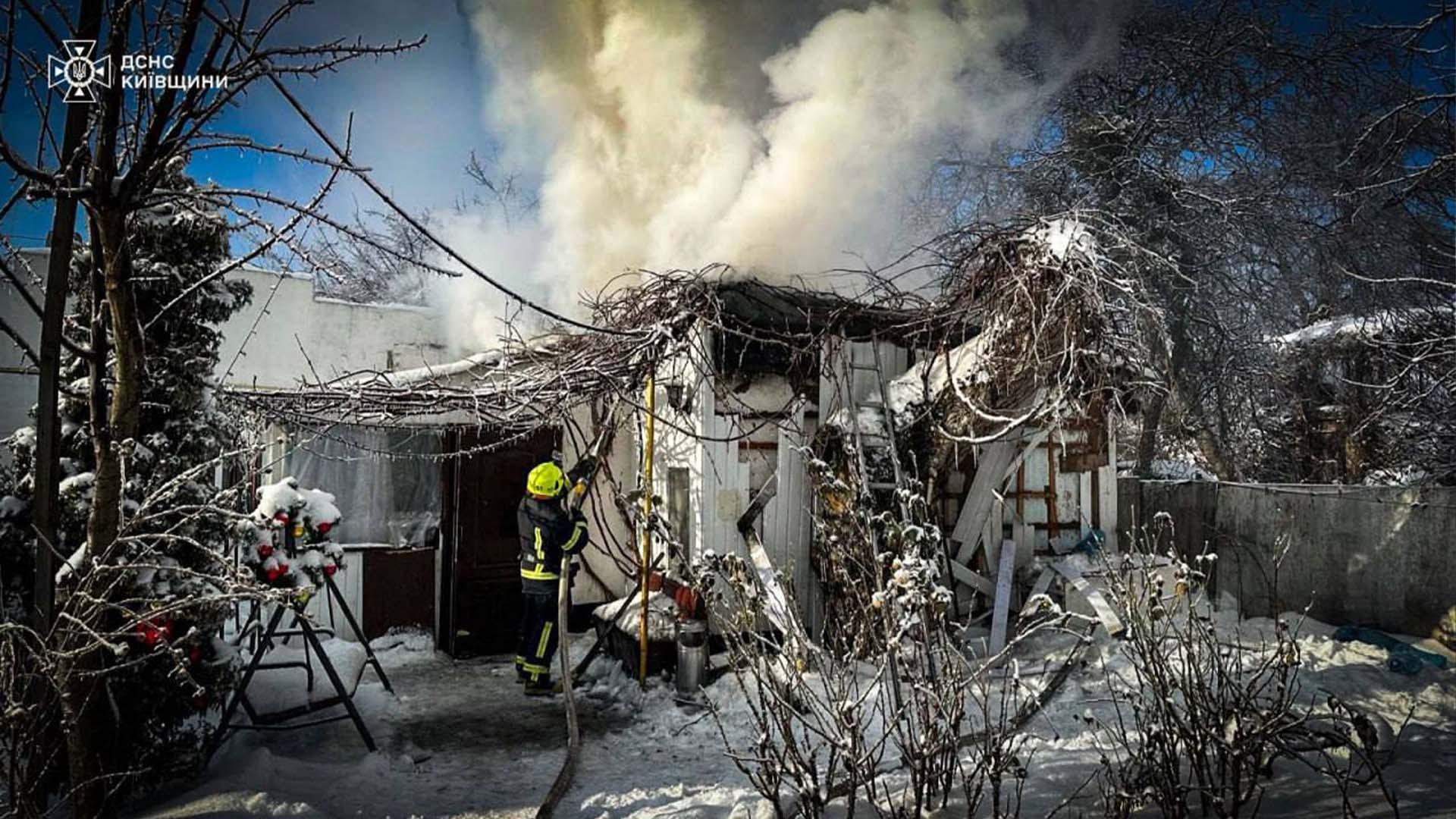 Пожежник гасить вогонь, який охопив невелику дерев'яну господарську споруду