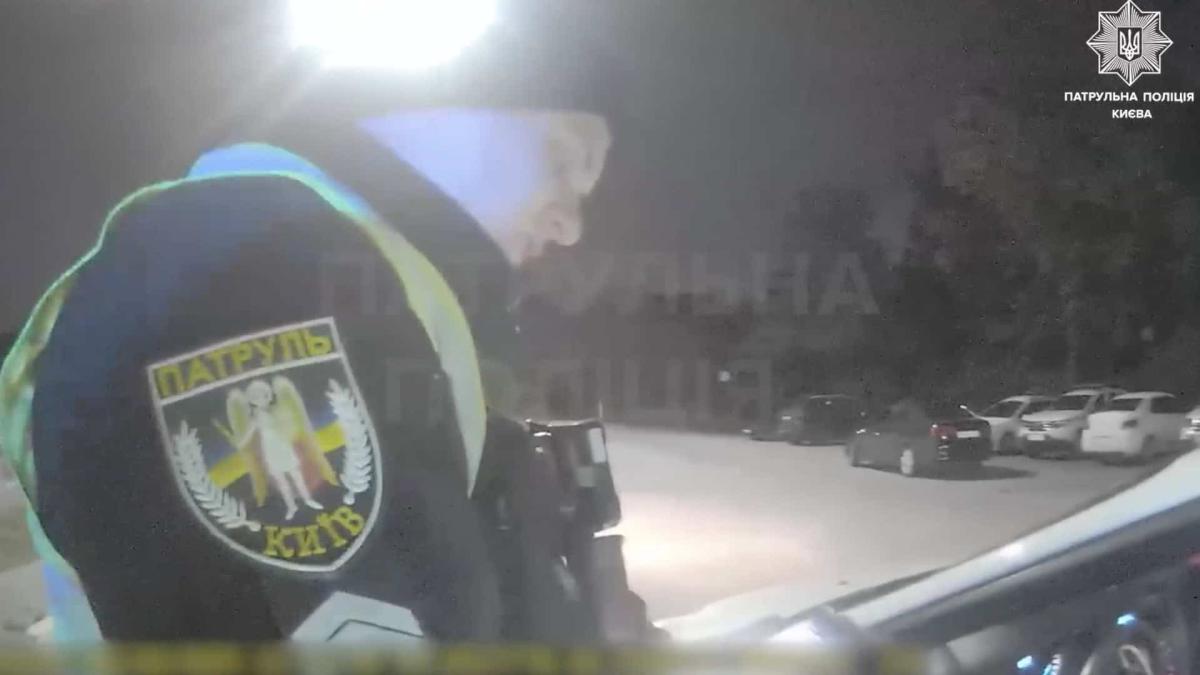 Поліція Києва прокоментувала інцидент на блокпості (відео) Скриншот з відео з бодікамер поліції, чоловік поліцейський стоїть біля машини в темряві
