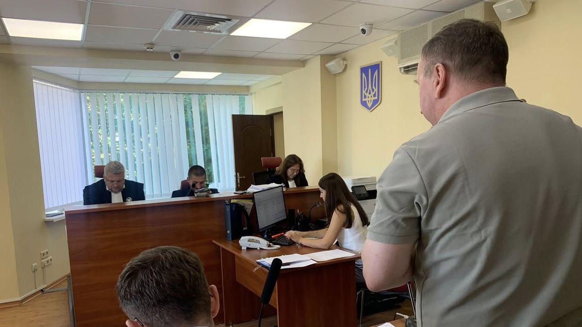 Судове засідання у залі суду: судді та секретар за столом, перед ними виступає чоловік