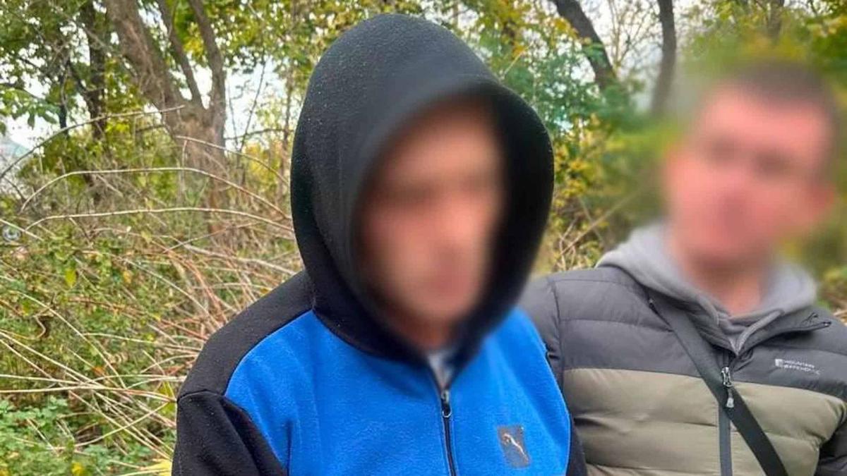 На Подолі чоловік убив знайомого й сховав тіло під листям Два чоловіки в лісі із заблюреними обличчями в осінньому одязі,