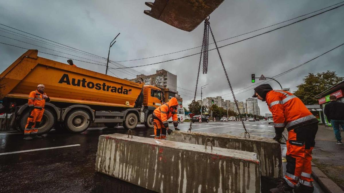 Капремонт Харківського шосе розпочали без необхідних дозволів — активіст Працівники в яскравих помаранчевих комбінезонах встановлюють бетонні блоки