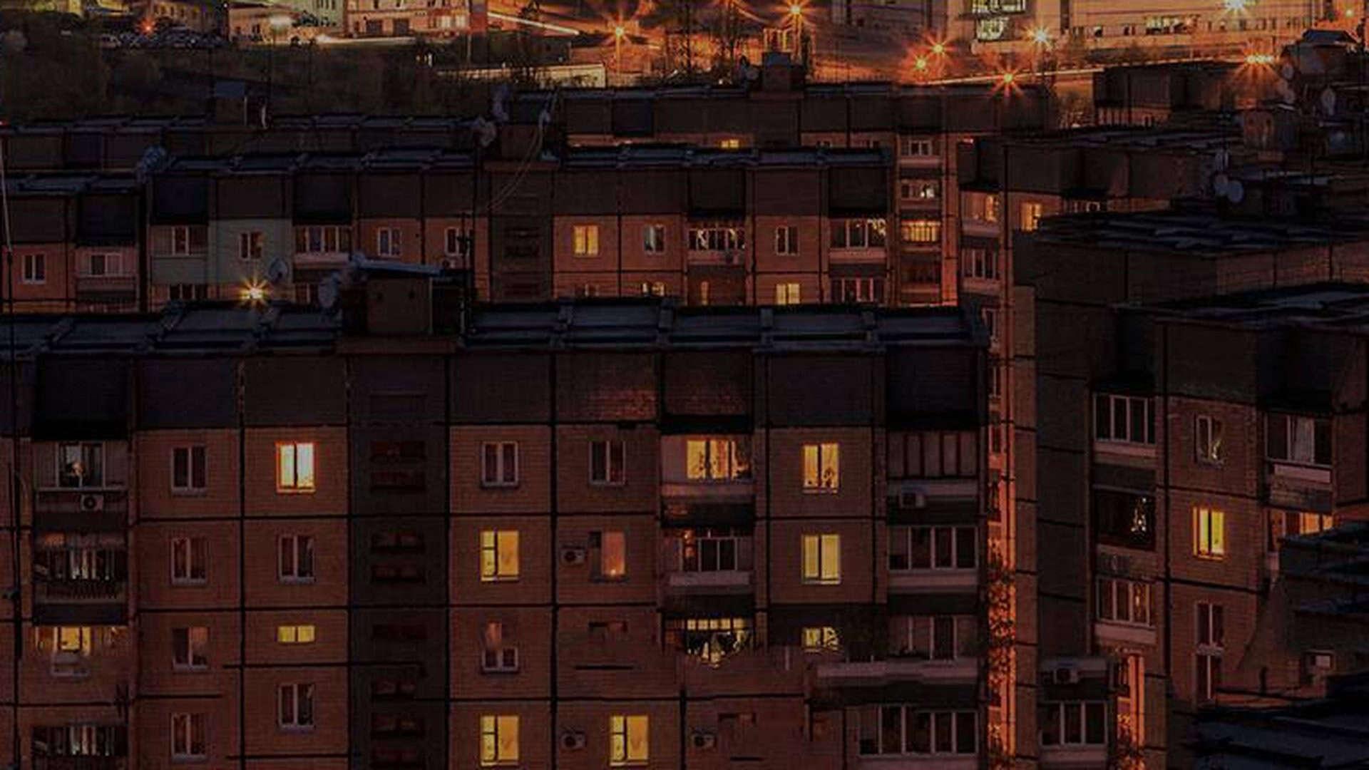 Багатоповерхівки в темноті і у вікнах горить світло