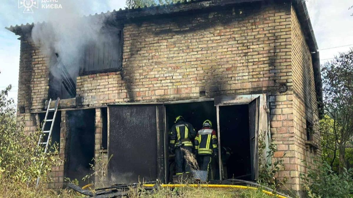 У Дарницькому районі під час пожежі загинула людина — ДСНС Двоє рятувальників гасять пожежу у двоповерховому цегляному гаражі в Києві, з якого йде густий дим