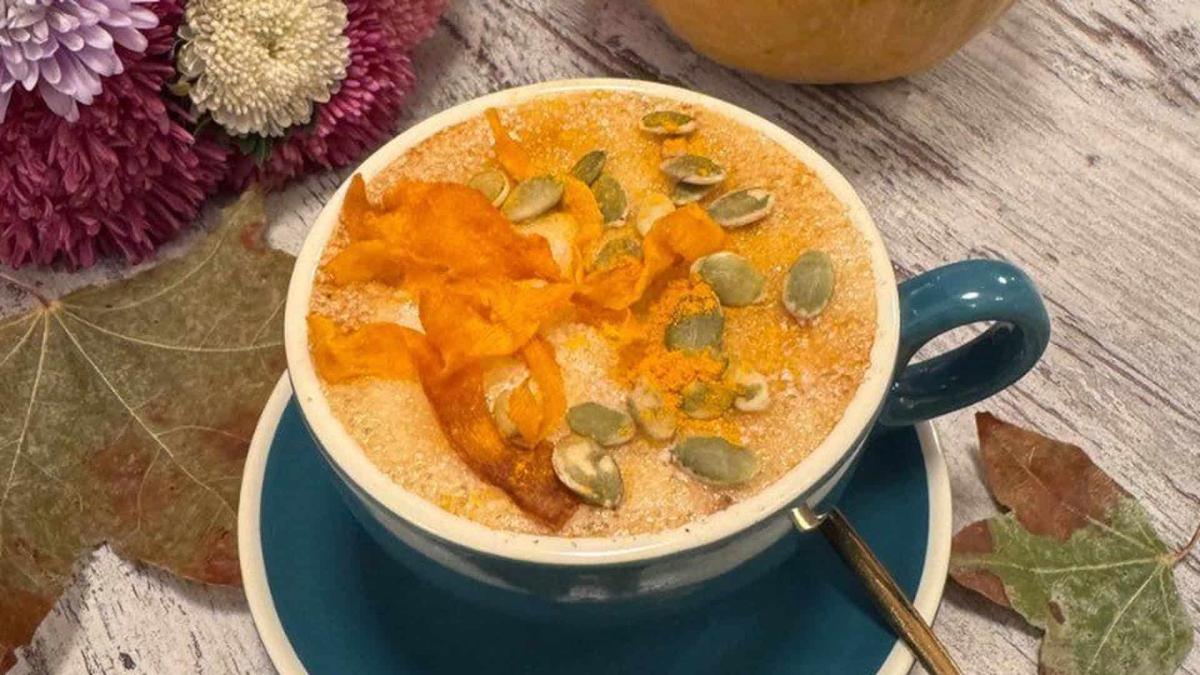 Гарбузовий лате в синій чашці, прикрашений насінням і гарбузовими чипсами