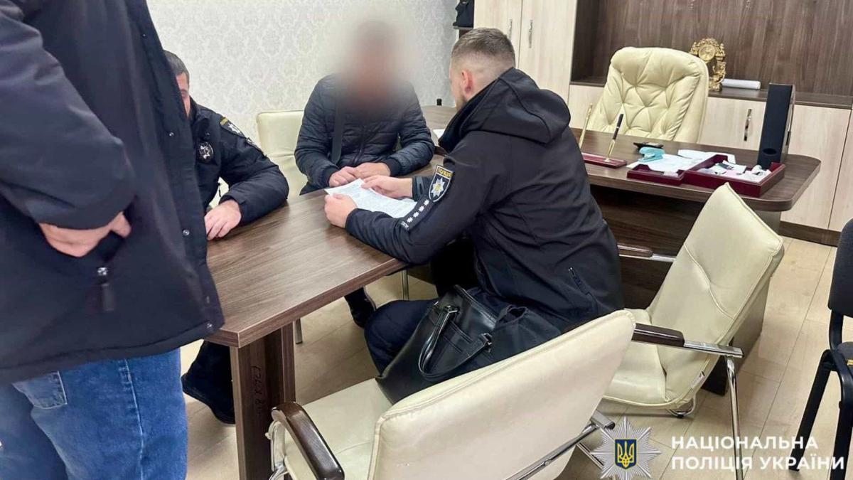 Правоохоронці сидять за столом в офісі поряд із підозрюваним у скоєнні злочину