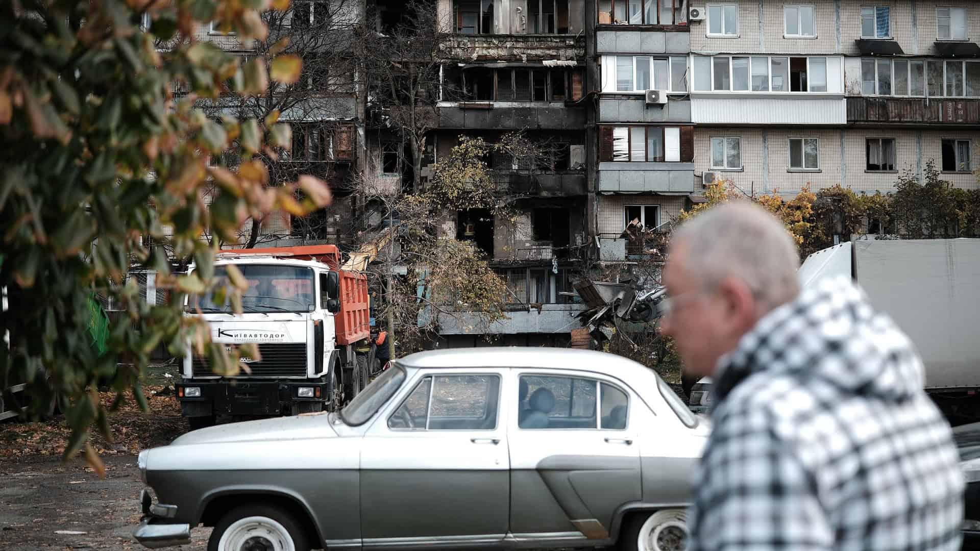 Волонтери, які відновлюють будинки після обстрілів: «КМДА не дала майже нічого — усе купуємо самі» (відео) Чоловік проходить повз зруйнованої багатоповерхівки у Києві, біля будинку стоїть вантажівка, яка вивозить будівельні завали після прильоту