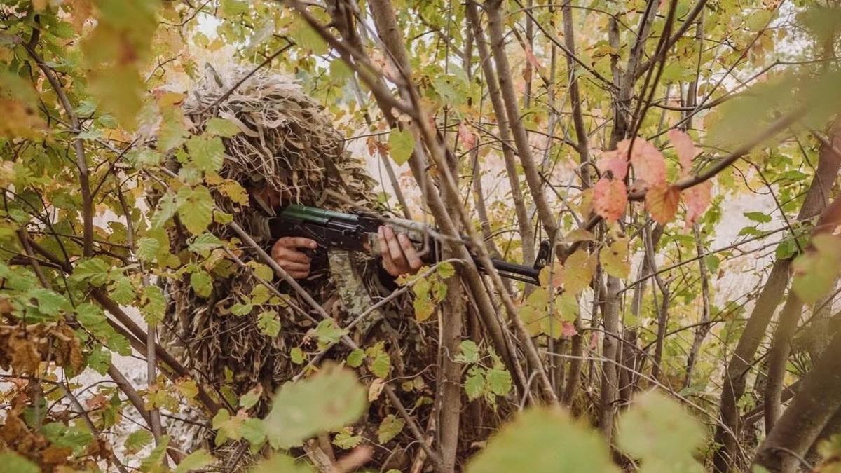 Снайпер в маскуванні сидить в кущах
