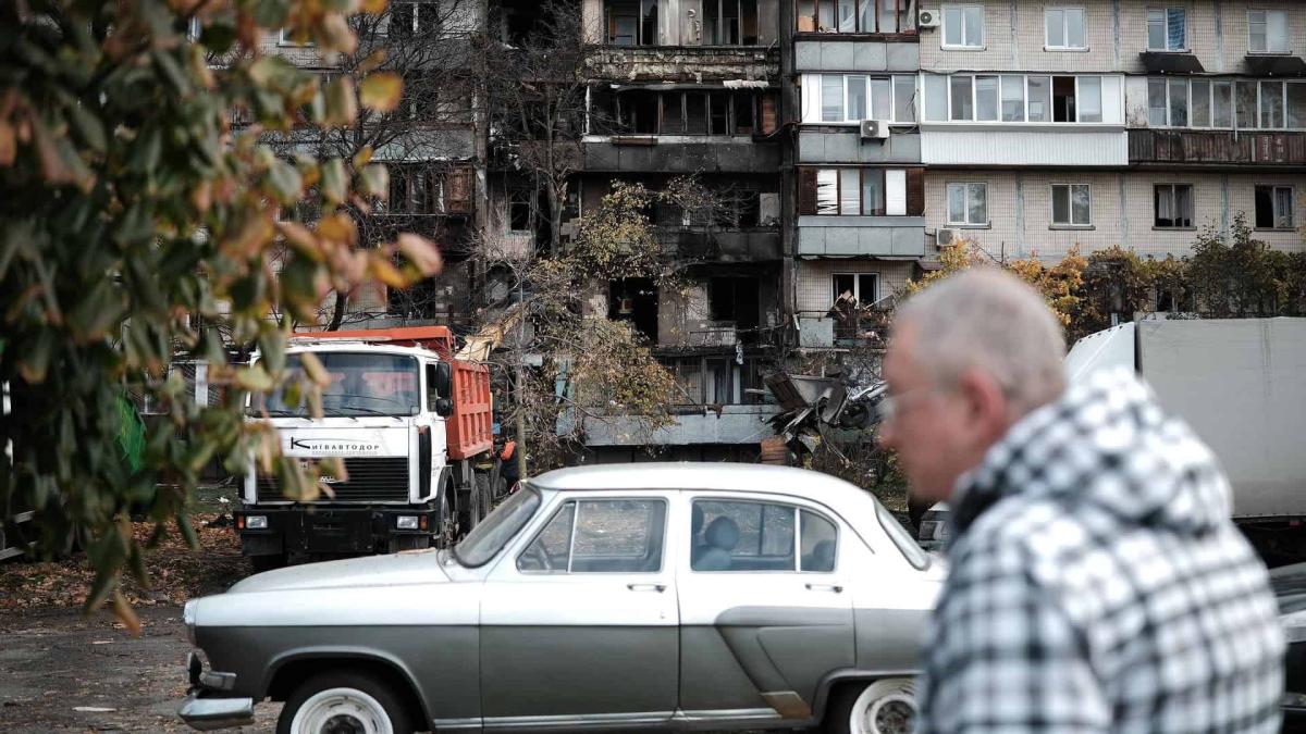 22 000 киян отримали компенсацію за пошкоджене житло Чоловік проходить повз зруйнованої багатоповерхівки у Києві, біля будинку стоїть вантажівка, яка вивозить будівельні завали після прильоту