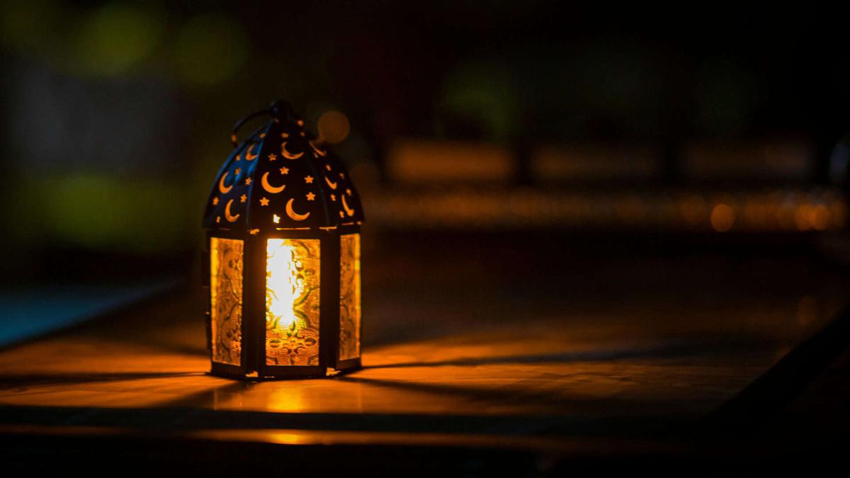 Невеличка лампадка зі свічкою стоїть на столі у темряві