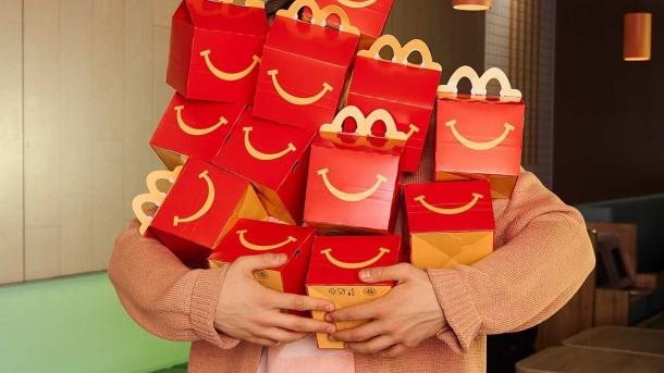 Людина тримає стопку червоних коробок McDonald's Happy Meal