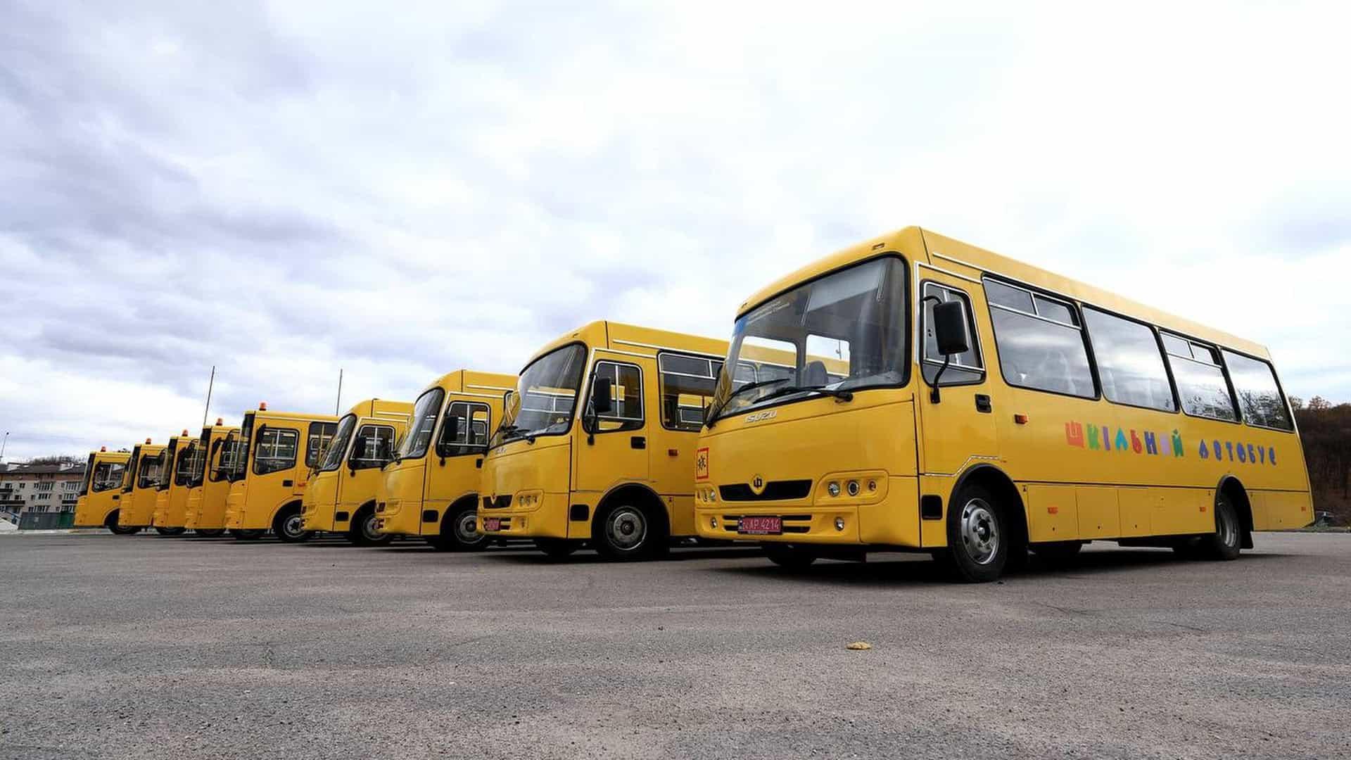 Шкільні автобуси - жовті типу "Богдана" стоять в ряд на стоянці, їх 9 штук.