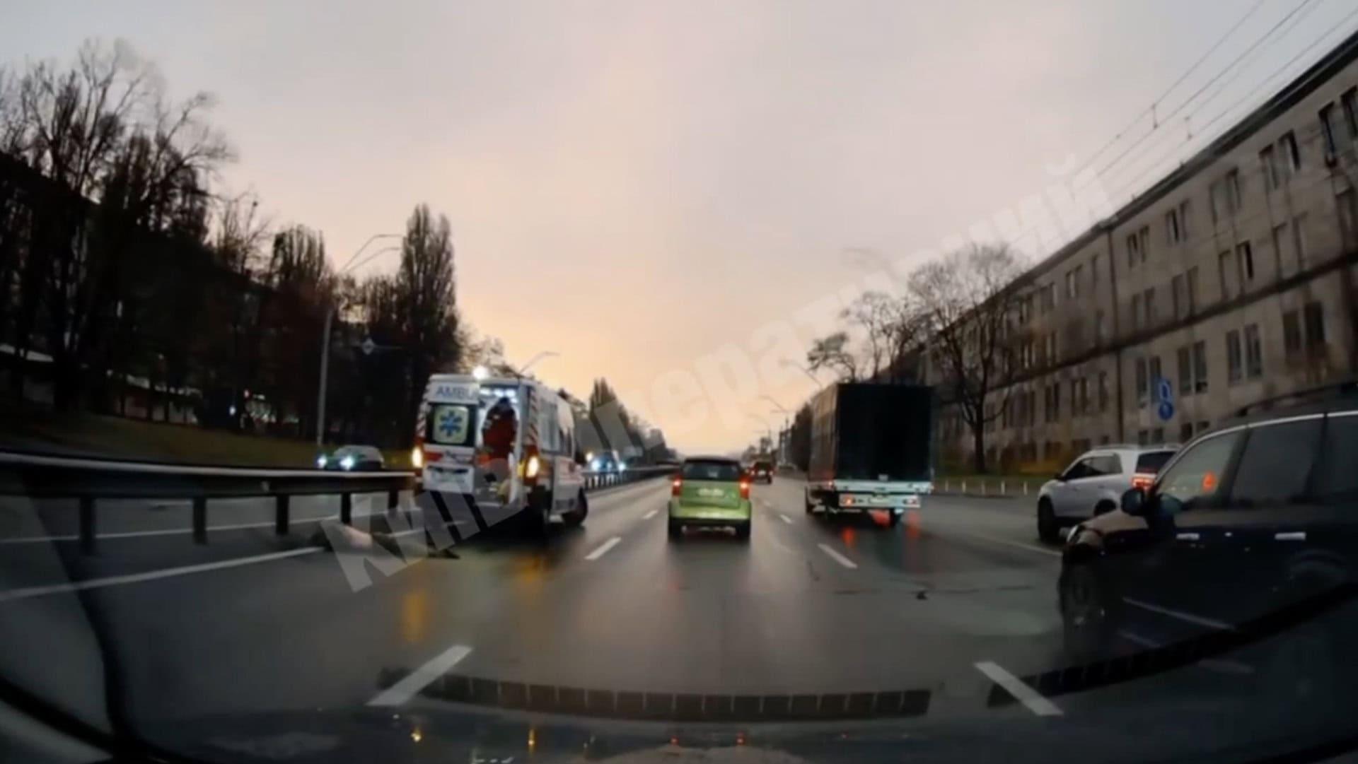 Вид із машини на мокру дорогу, де видно "швидку" та інші автомобілі під час сутінок