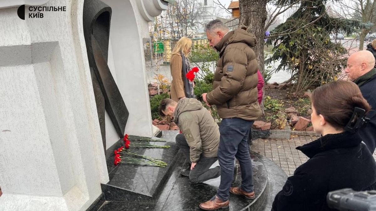 Кілька чоловіків принесли квіти до памʼятника червоній стрічці в Києві