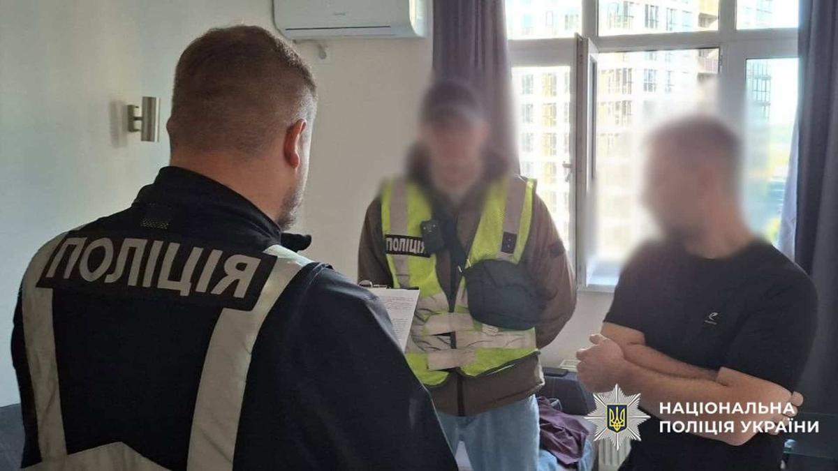 Легалізував 200 іноземців в Україні: у Києві затримали організатора схеми Двоє працівників поліції стоять в кімнаті та спілкуються з чоловіком, якому вручають підозру