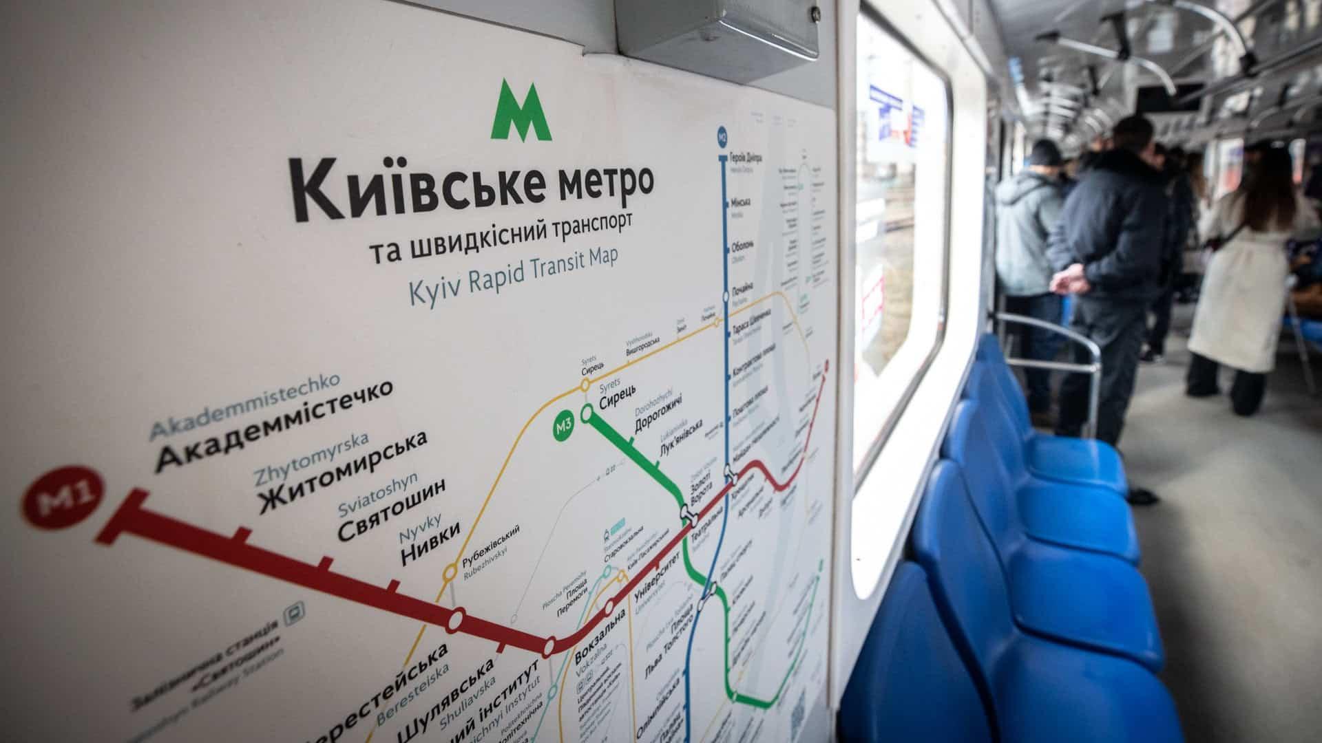 Київ потребує допомоги ШІ в умовах війни, але нові моделі помиляються в половині випадків Карта гілок київського метро на фоні людей, які стоять у вагоні