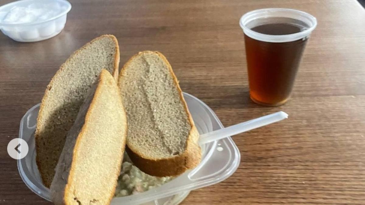 Чорний хліб нарізаний шматочками лежить на тарілці, поряд стоїть чай в одноразовому стаканчику